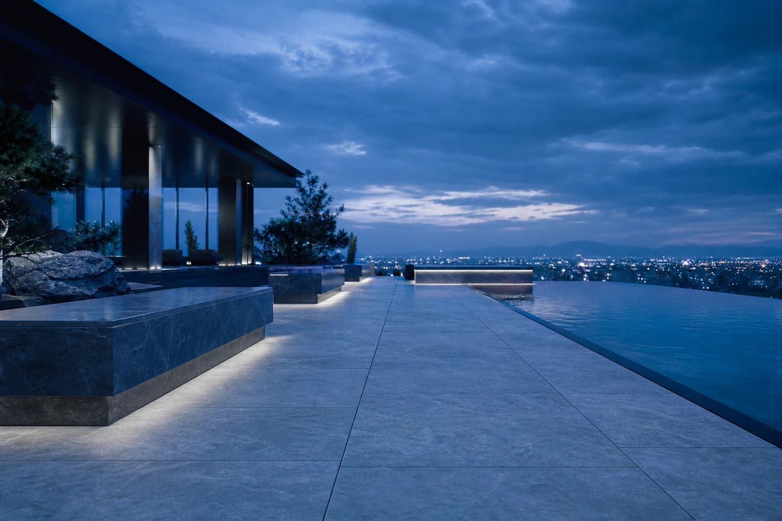 Large-format porcelain pavers on a hotel roof terrace at dusk beside an infinity pool.