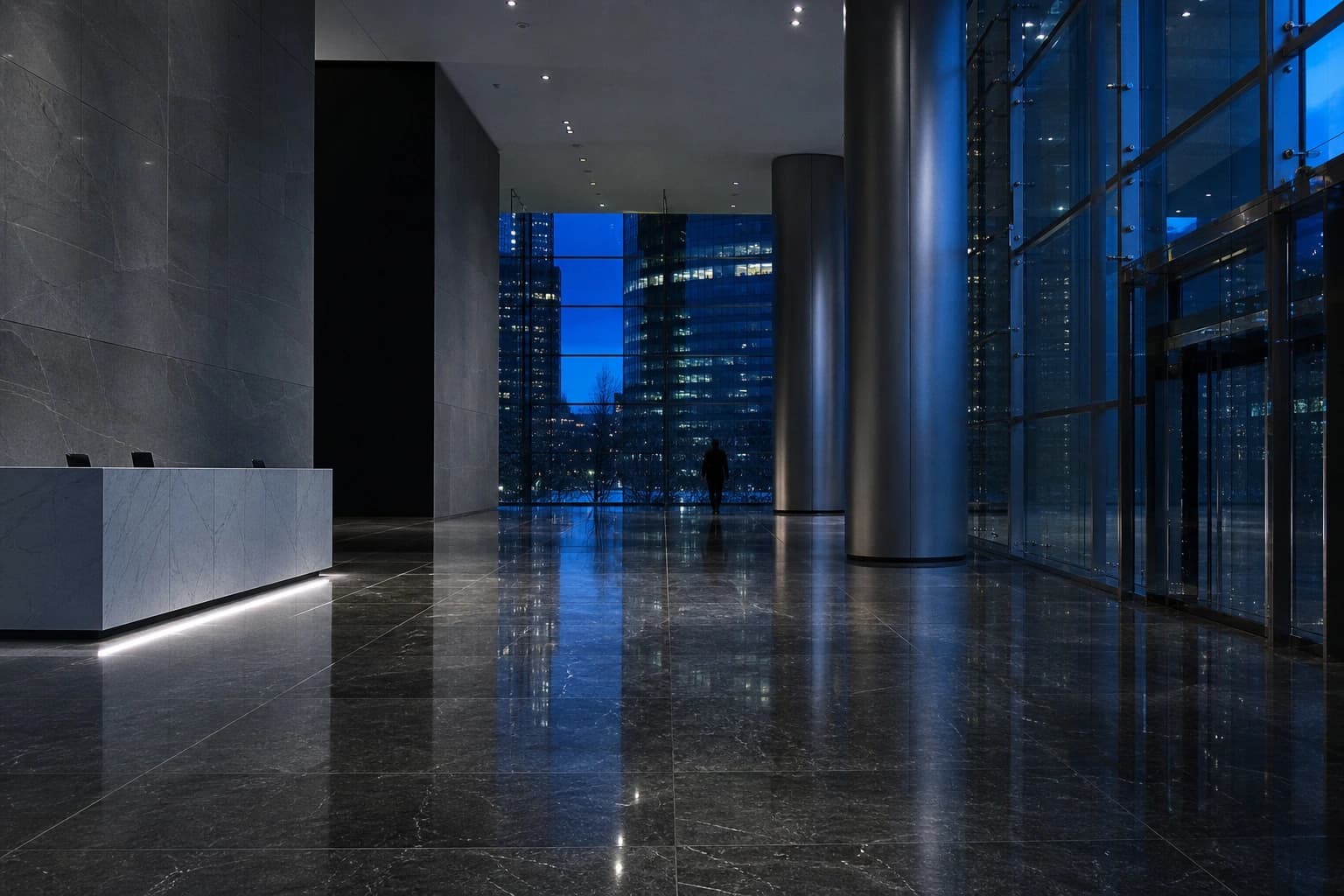 An office tower lobby at dusk with a mirror-polished dark stone floor reflecting the skyline.